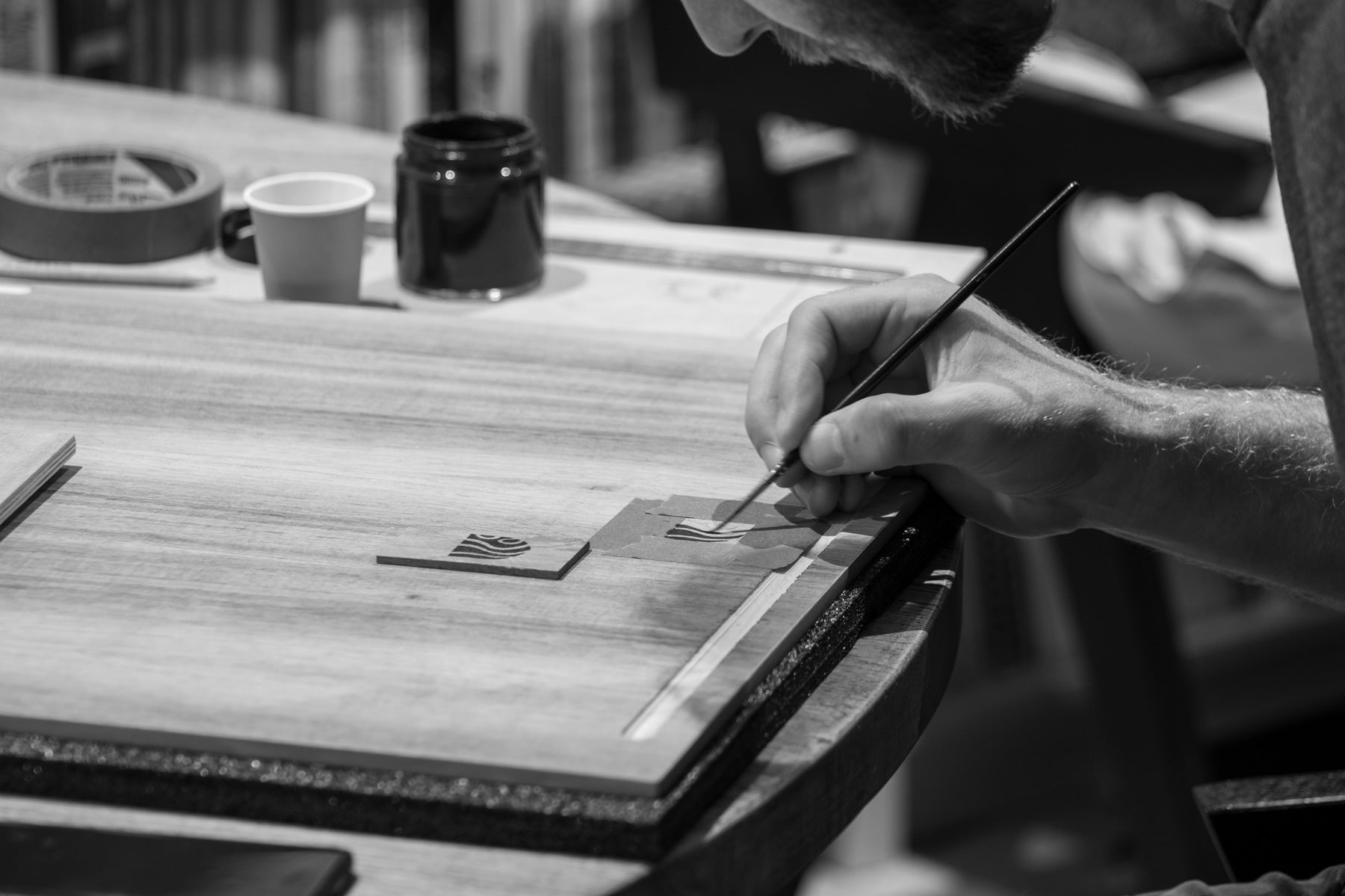 Phillip carefully paints the Woodfort Case logo onto the inside of a case's wooden panel.